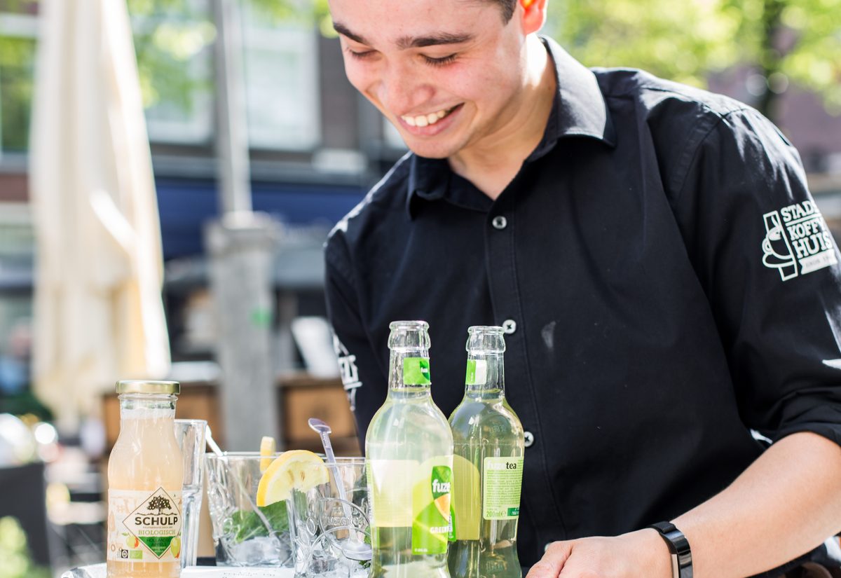 Medewerker serveert drankjes op een terras